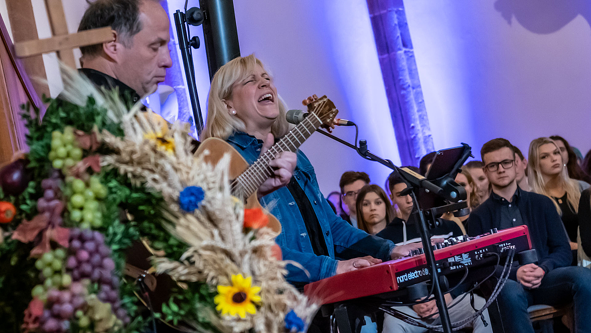 Ein Musiker stehend mit Gitarre, neben ihm eine Sängerin am E-Piano.