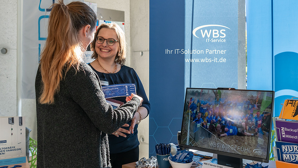 Vertreterin der Firma WBS im Gespräch mit einer Standbesucherin.